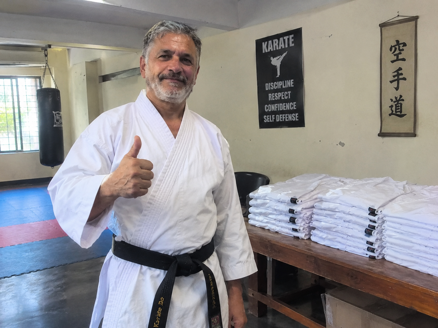 Senior karate instructor showcasing a bulk dojo uniform order